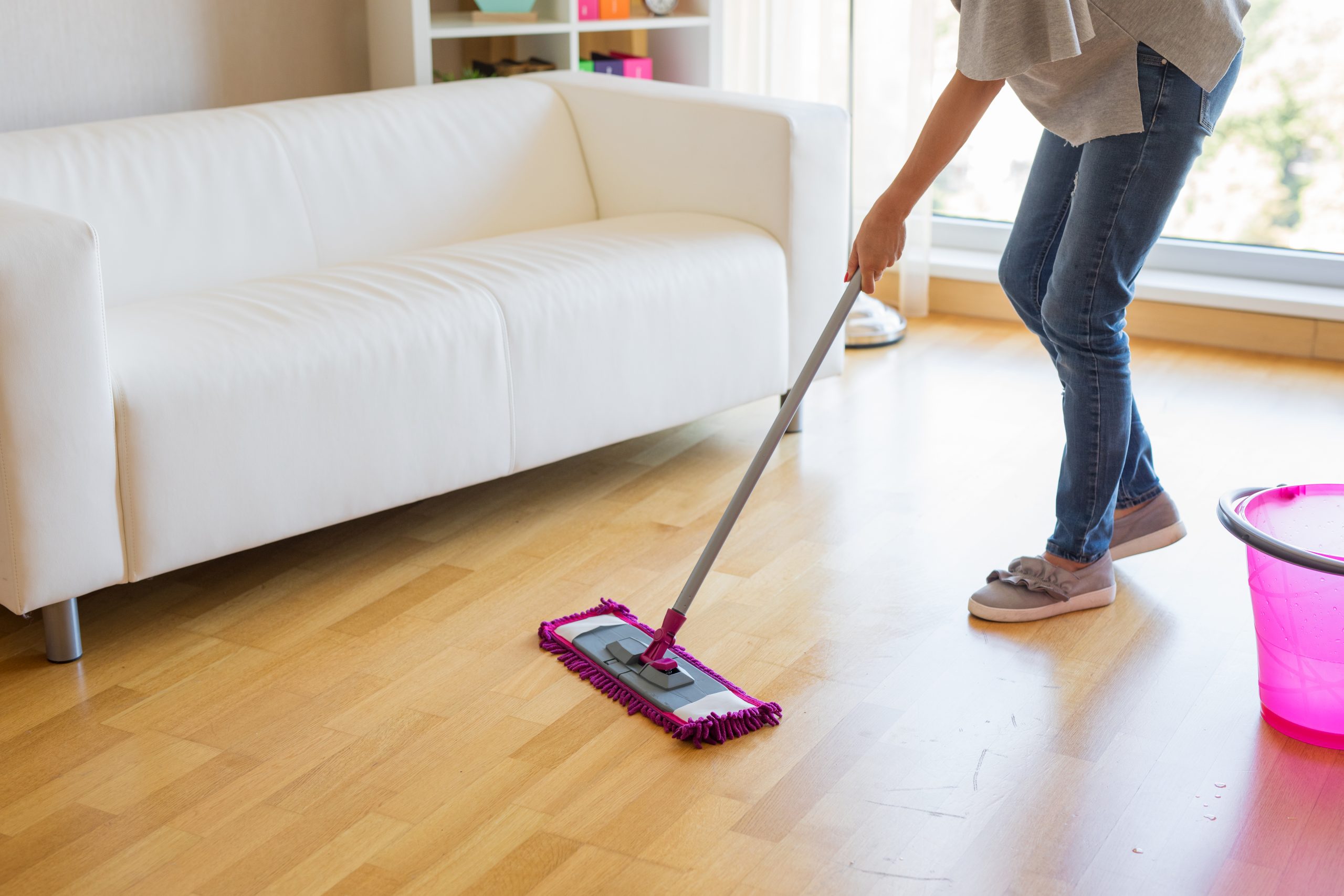 Homeowner mopping a newly finished oak hardwood floor after Professional Wood Floor Sanding, keeping the surface dust-free and gleaming.