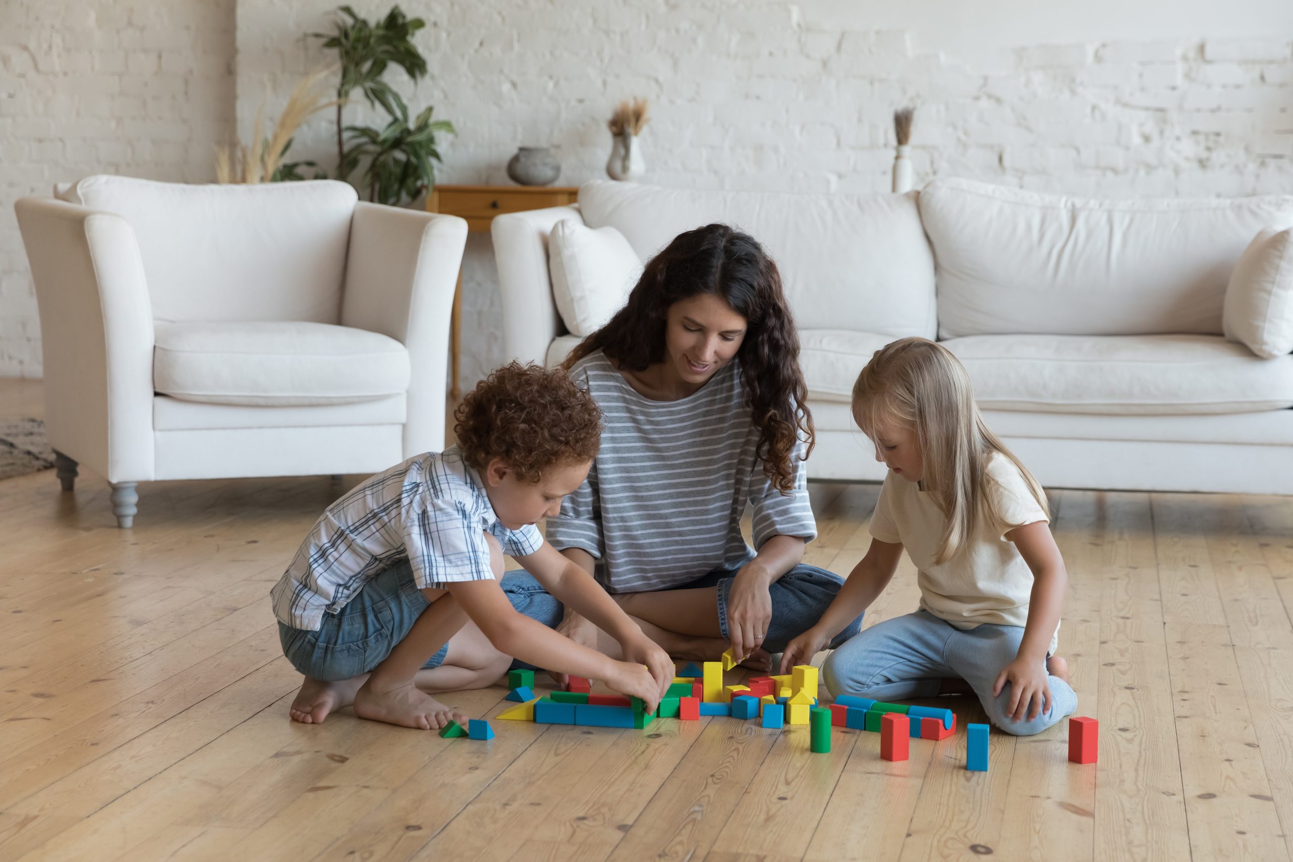 Mother and two children playing with colourful blocks on newly refinished softwood pine floorboards after Wood Floor Sanding.