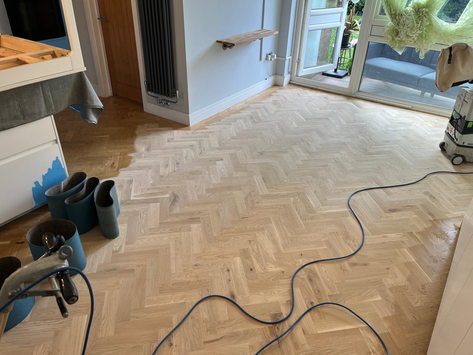 Floor Sanding Preparation Checklist in progress on a light oak herringbone parquet wood floor, with sanding belts, cables and dust-free machine set up.