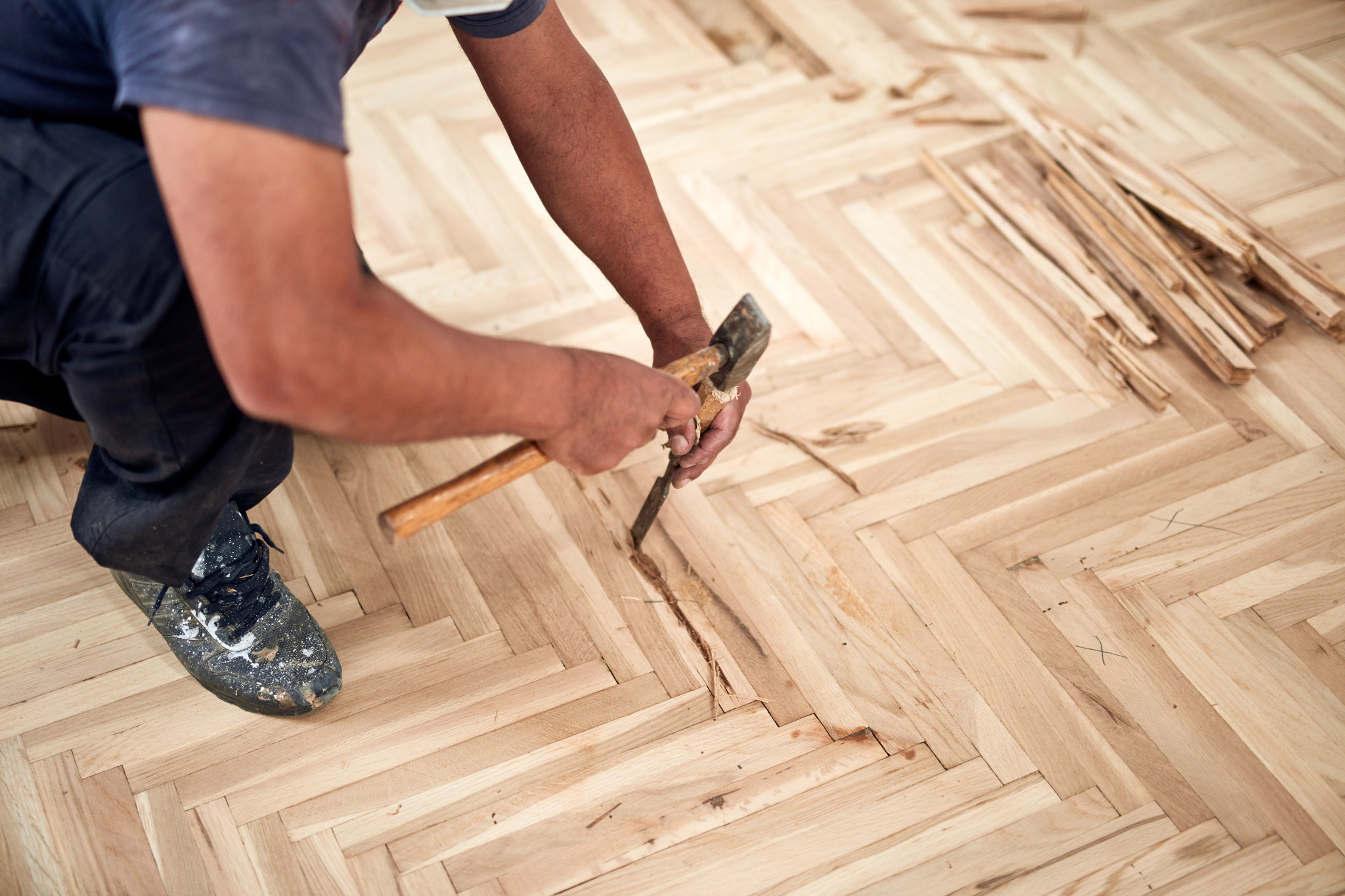 Floor Sanding Preparation Checklist shown as a professional repairs damaged oak herringbone parquet floor blocks before sanding.