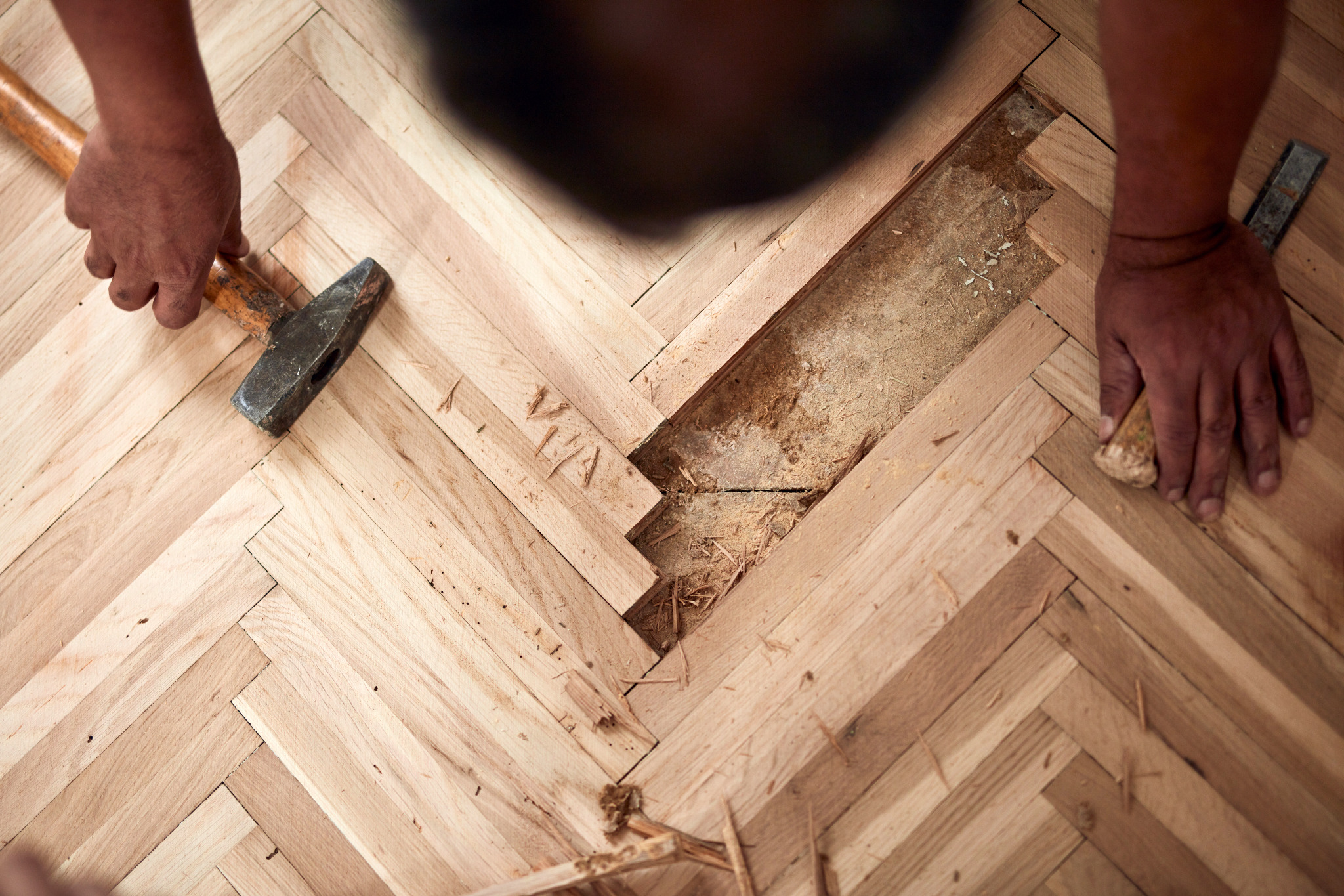 Floor Sanding Preparation Checklist in action as a professional repairs gaps in an oak herringbone parquet floor before sanding.
