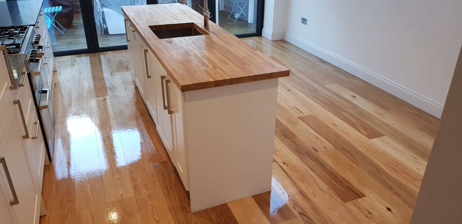 Worktop Refinishing on an oak butcher block island worktop with freshly restored solid oak wood floor, both showing a high-gloss, like-new finish.