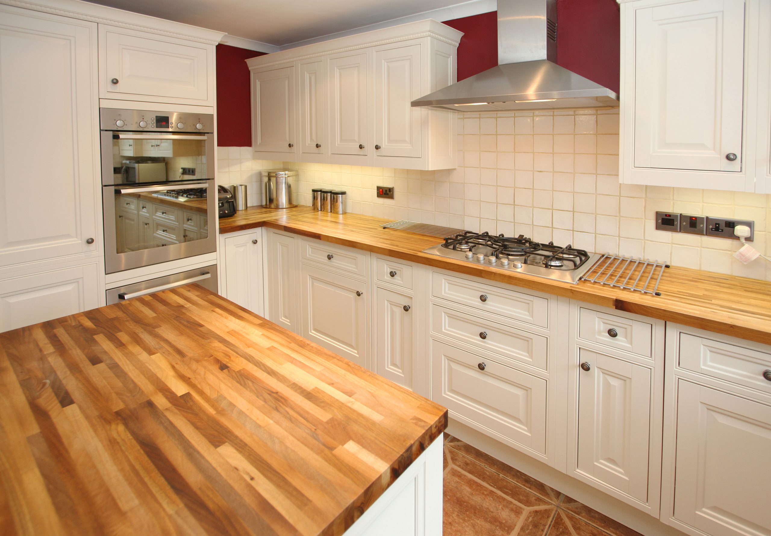 Worktop Refinishing in a classic kitchen with freshly restored oak butcher block worktops and a terracotta ceramic tile floor, creating a warm, elegant look.