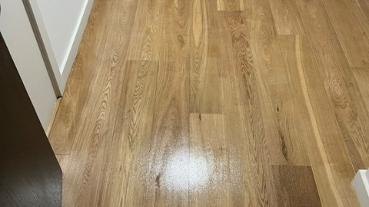Hardwood Floor Refinishing result showing a light oak hardwood plank floor in a hallway with a smooth, even finish that highlights the natural grain.